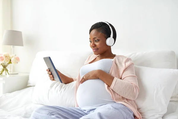 Femme enceinte dans un casque avec tablette pc — Photo