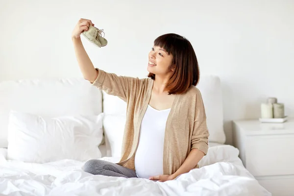 Mujer embarazada feliz con botines en la cama en casa — Foto de Stock