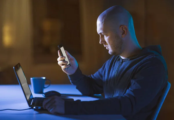 Hacker con portátil y smartphone en habitación oscura —  Fotos de Stock