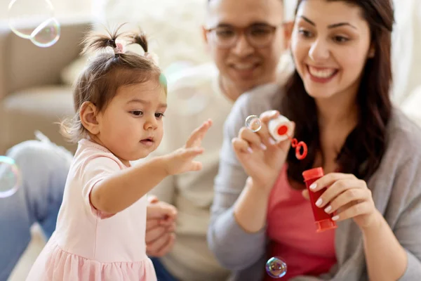 Family with soap bubbles playing at home — Stock Photo, Image