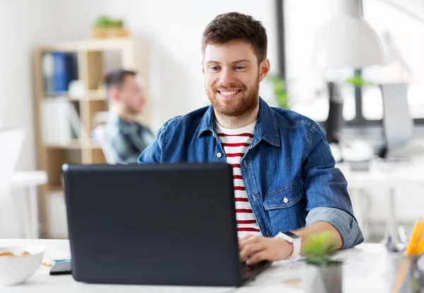 Homme créatif souriant avec ordinateur portable travaillant au bureau — Photo