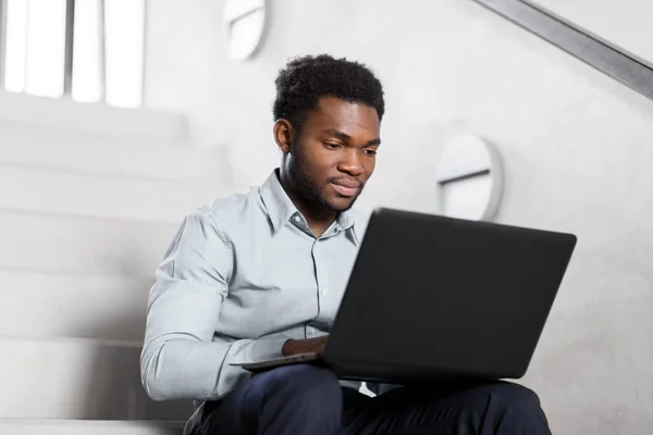 Empresário afro-americano com laptop no escritório — Fotografia de Stock