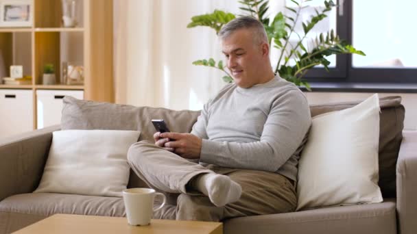 Homem com smartphone beber café em casa — Vídeo de Stock