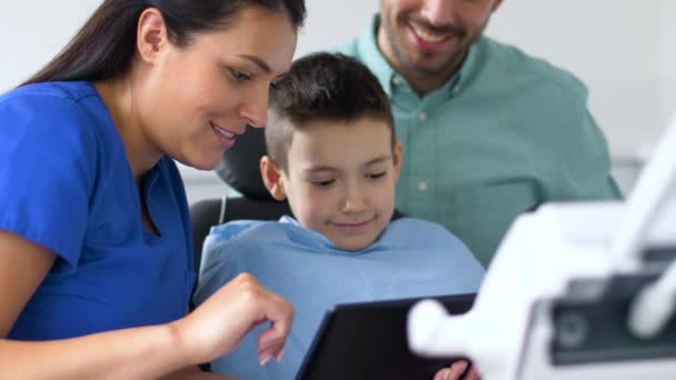 Dentista mostrando tablet pc para criança na clínica odontológica — Vídeo de Stock