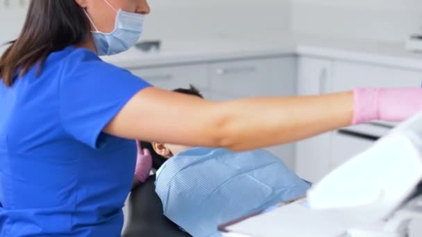 Dentista feminina com menino paciente na clínica odontológica — Vídeo de Stock