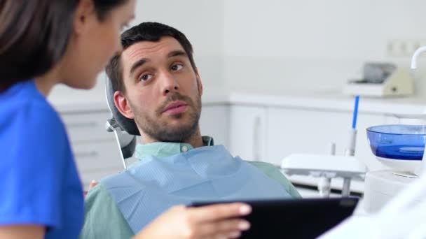 Стоматолог и пациент обсуждают лечение зубов — стоковое видео