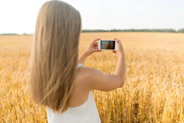 Menina tirando foto por smartphone no campo de cereais — Fotografia de Stock