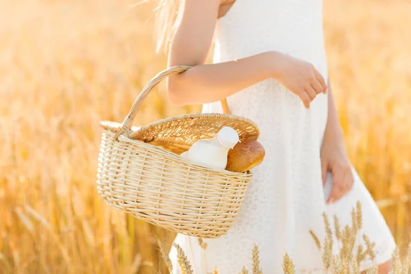 Niña con pan y leche en cesta en el campo de cereales — Foto de Stock
