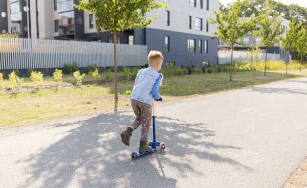 Glücklicher kleiner Junge fährt Roller in der Stadt — Stockfoto