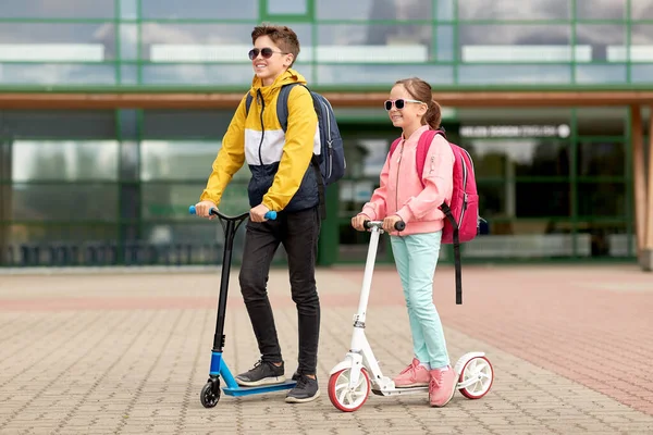 Niños de escuela feliz con mochilas y scooters —  Fotos de Stock