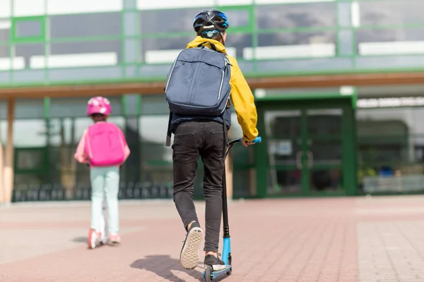 Děti školy s batohy na skútrech — Stock fotografie