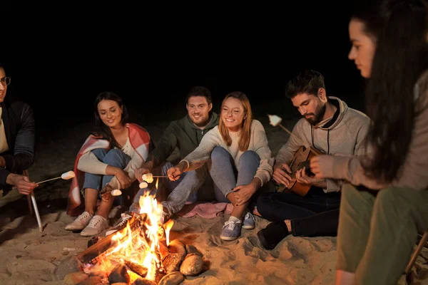 Друзі смажать зефір на вогні табору на пляжі — стокове фото