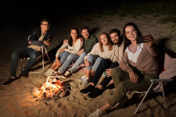 Glückliche Freunde machen Selfie am Lagerfeuer am Strand — Stockfoto