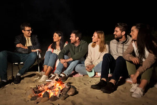 一群朋友坐在海滩上的篝火 — 图库照片
