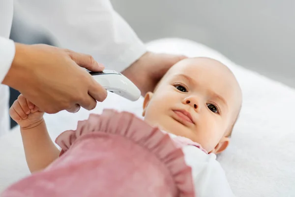 Läkare med termometer mäter barnens temperatur — Stockfoto