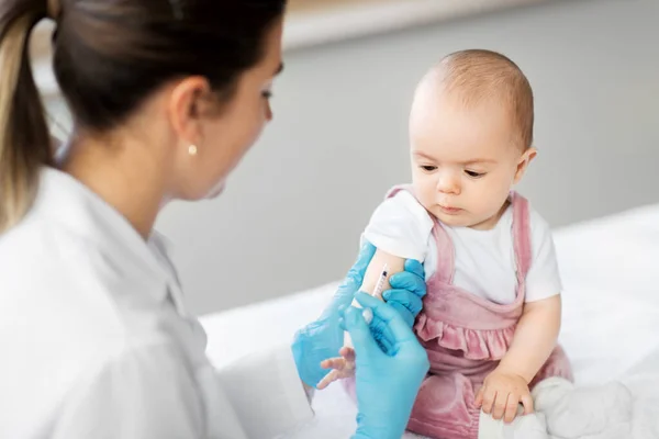 Lékař vyrábějící vakcíny pro dětskou pacientku na klinice — Stock fotografie