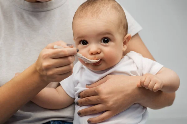 Close up de mãe com colher alimentando pequeno bebê — Fotografia de Stock