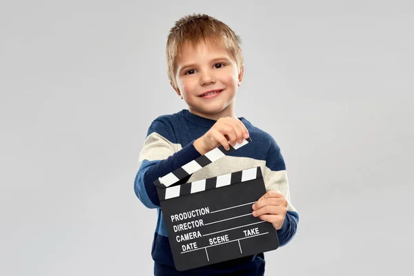 Glad liten pojke med clapperboard i studio — Stockfoto
