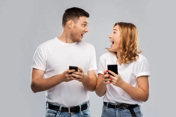 Casal feliz em camisetas brancas com smartphones — Fotografia de Stock