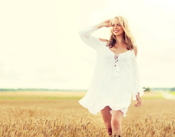 Usmívající se mladá žena v bílých šatech na obilném poli — Stock fotografie
