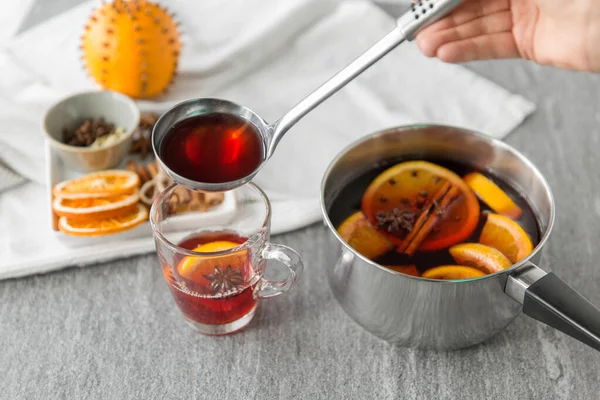 Mano con mestolo versando vin brulè caldo a bicchiere — Foto Stock