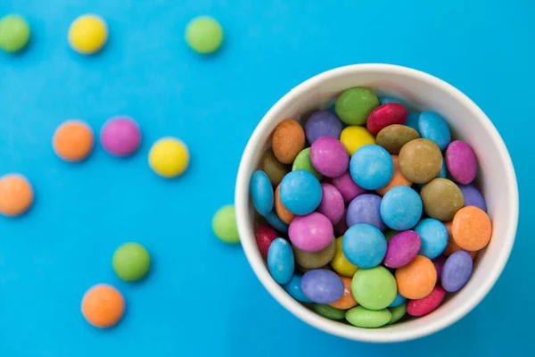 Gotas de doces em copo de papel no fundo azul — Fotografia de Stock