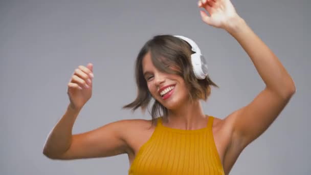 Glad skrattande ung kvinna i hörlurar dans — Stockvideo