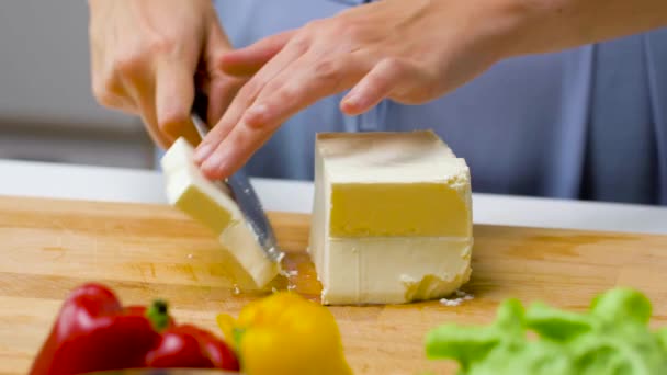 Woman with knife chopping feta cheese on board — ストック動画