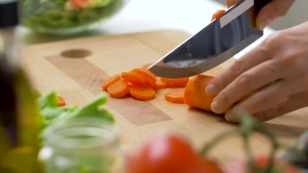 Woman chopping carrot with kitchen knife at home — Stock Video