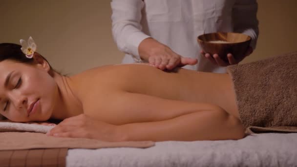Mooie jonge vrouw het hebben van zout massage in spa — Stockvideo