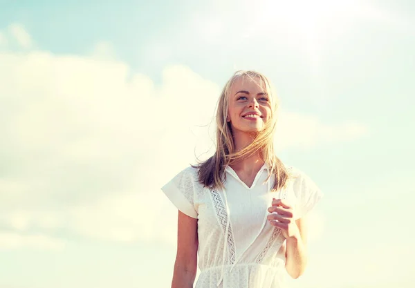 Lächelnde junge Frau im weißen Kleid über blauem Himmel — Stockfoto