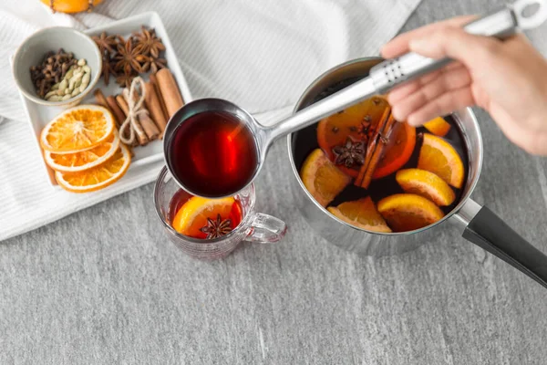 Mano con mestolo versando vin brulè caldo a bicchiere — Foto Stock