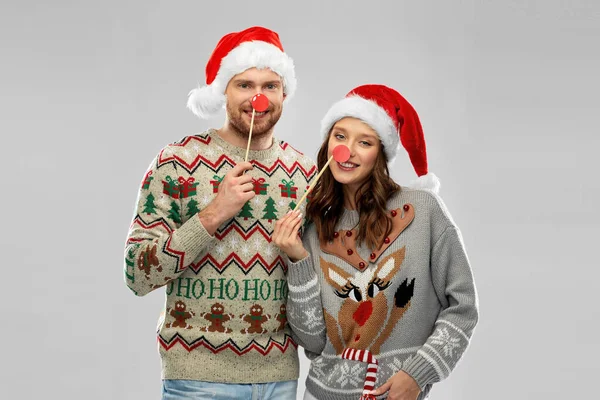 Casal com adereços de festa de Natal em camisolas feias — Fotografia de Stock