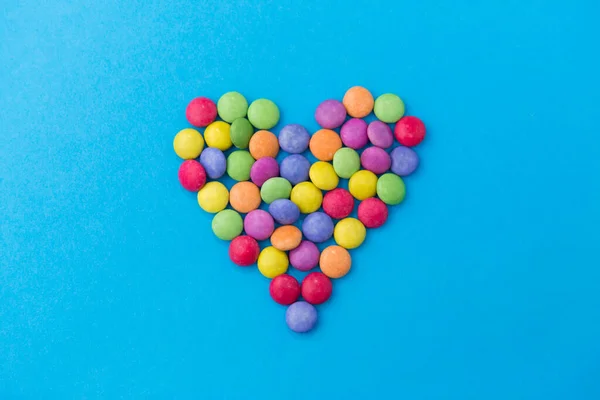 Gotas de caramelo en forma de corazón sobre fondo azul —  Fotos de Stock