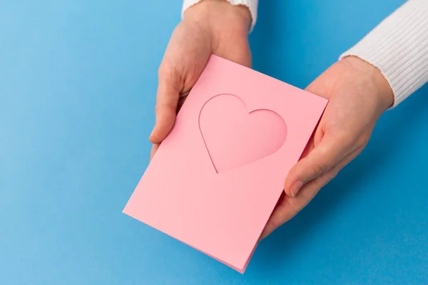 Hands holding greeting card with heart — Stock Photo, Image