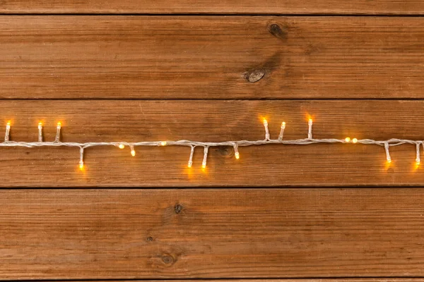 Guirnalda de Navidad luces sobre fondo de madera — Foto de Stock