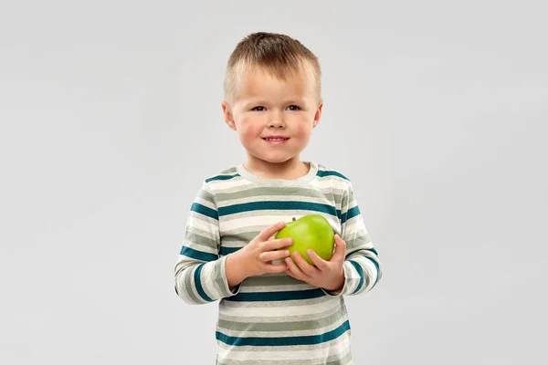 Portret uśmiechniętego chłopca trzymającego zielone jabłko — Zdjęcie stockowe