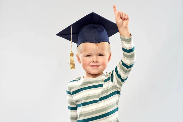 Little boy in mortar board pointing finger up — Stock Photo, Image