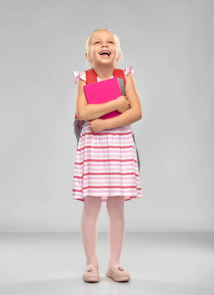 Feliz niña estudiante con la bolsa de la escuela y libro — Foto de Stock