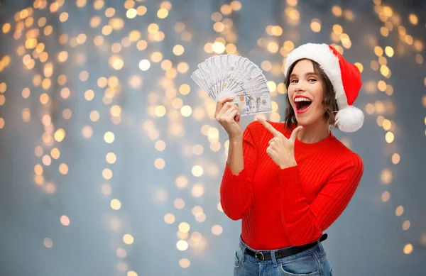 Donna felice in cappello di Babbo Natale con i soldi a Natale — Foto Stock