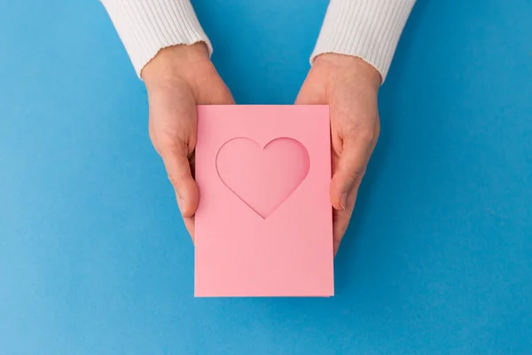 Mãos segurando cartão de saudação com coração — Fotografia de Stock