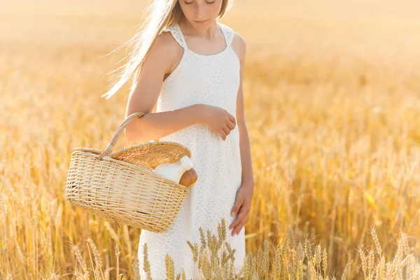 Niña con pan y leche en cesta en el campo de cereales —  Fotos de Stock