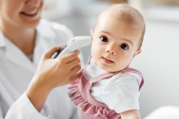 Médico con termómetro mide la temperatura del bebé —  Fotos de Stock