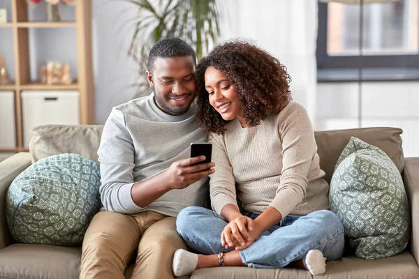 Pareja afroamericana con smartphone en casa — Foto de Stock