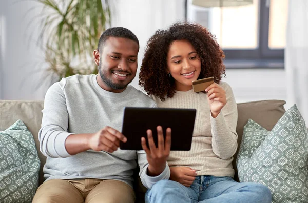 Casal com tablet pc e cartão de crédito em casa — Fotografia de Stock