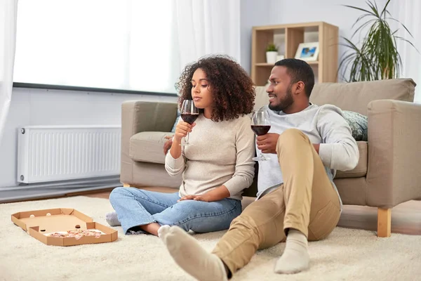 Casal feliz com vinho e pizza takeaway em casa — Fotografia de Stock