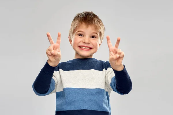 Маленький хлопчик в смугастому пуловері, що показує мир — стокове фото