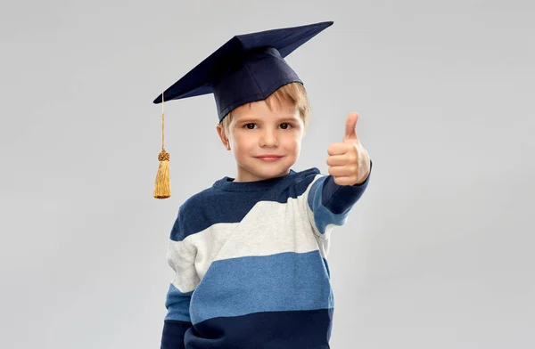 Kleine jongen in mortierbord tonen duimen omhoog — Stockfoto