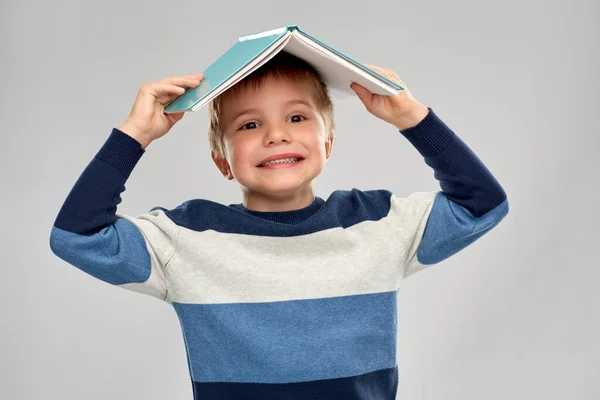 Petit garçon avec un toit de livre sur la tête — Photo