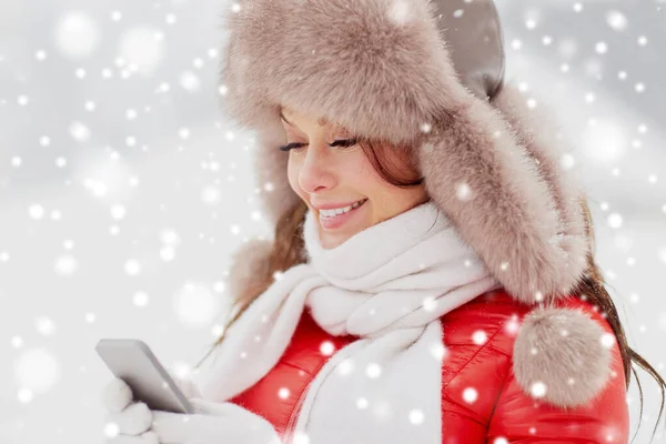 Happy woman in winter fur hat with smartphone — Stock Photo, Image